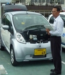 「i-MiEV」（アイミーヴ）を前に、説明を行なっている様子